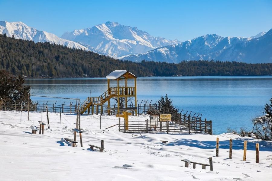 : Rara Lake in winter with snow-covered playground and pine forests